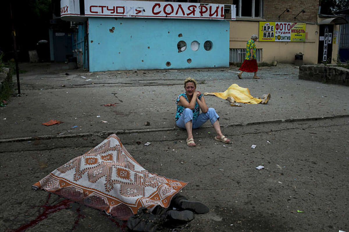 A woman cries near to the bodies of people, among whom were family members, who were killed during shelling by Ukrainian government troops in Luhansk, eastern Ukraine, Friday, July 18, 2014. The fighting between the government and pro-Russia separatists in Luhansk continued as world leaders called for an immediate cease-fire in eastern Ukraine on Friday and demanded speedy access for international investigators to the crash site of the Malaysia Airlines jetliner shot down over the country's battlefields. (AP Photo/Mikhail Ivanchenko)