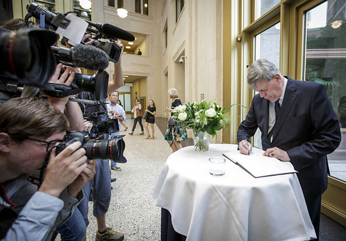 Dutch Justice Minister Ivo Opstelten signs a condolence register at the Ministry of Security and Justice in The Hague, Netherlands, Friday, July 18, 2014. Flags are flying half-staff across the Netherlands as the country mourns at least 173 of its citizens killed when a Malaysia Airlines passenger jet was shot down in eastern Ukraine on Thursday July 17. Opstelten called the Dutch death toll of at least 173, 'an almost unbelievable number. The terrible reality of this disaster is hitting home more and more.' Opstelten told reporters it is critical to establish the exact cause of the tragedy. 'Many of our countrymen and women have died. That is why it is also important that the Netherlands, as part of an international investigative team, can begin research as soon as possible at the location where the aircraft crashed.' (AP Photo/Phil Nijhuis)