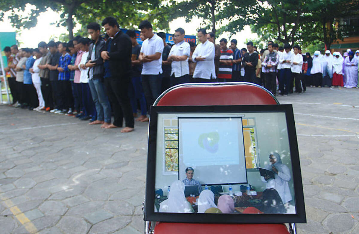 Students of Al Firdaus high school attend a prayer for their guest teacher John Paulissen, showed in the photo in the foreground, who was a passenger on board of the crashed Malaysia Airlines flight 17, in Solo, Central Java, Indonesia, Friday, July 18, 2014. The Malaysian jetliner that went down in war-torn Ukraine did not make any distress call, Malaysian Prime Minister Najib Razak said Friday, adding that its flight route had been declared safe by the global civil aviation body. (AP Photo)