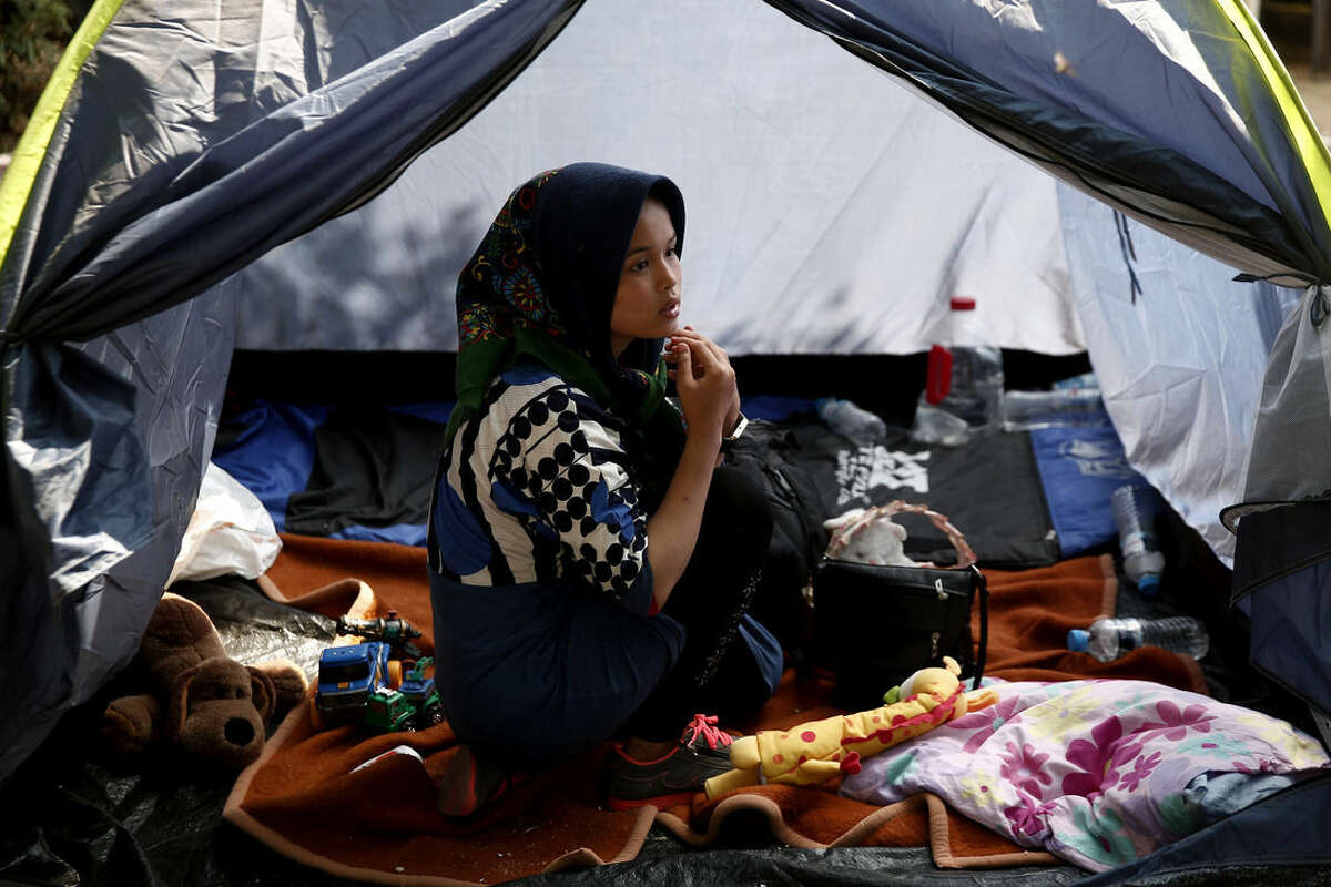 A migrant sits inside a tent at a park as she waits to be transferred along with other migrants to a organized camp which has been set up by the Greek state a few miles from the centre of Athens, Sunday, Aug. 16, 2015. Greek authorities say they have started resettling migrants living in tents in a park in the capital Athens, but many are wary of such a move and have moved to directions unknown thus far. (AP Photo/Yorgos Karahalis)