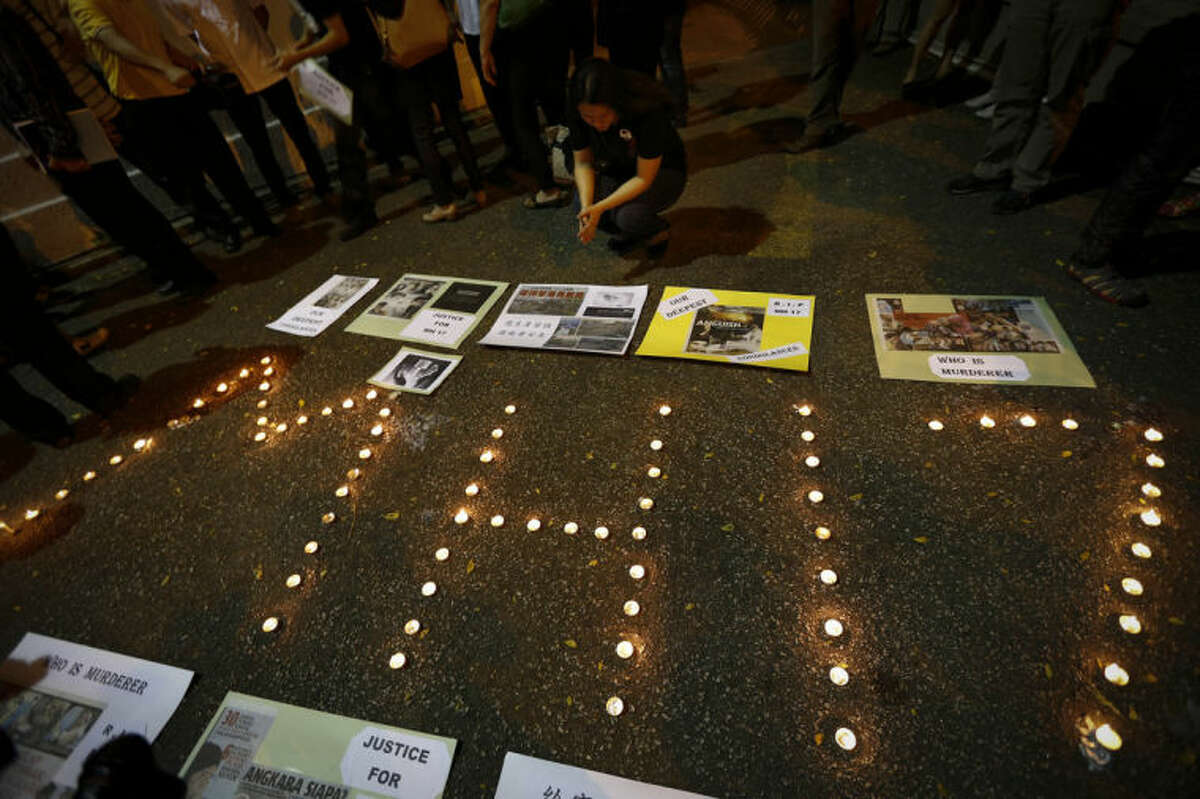 A woman looks at newspaper cuttings at a candlelight vigil for the victims of Malaysia Airlines Flight 17 in Kuala Lumpur, Malaysia, Saturday, July 19, 2014. Malaysian Transport Minister Liow Tiong Lai said the country is "deeply concerned" that the site in Ukraine where the Malaysia Airlines jetliner was shot down with 298 people onboard "has not been properly secured. (AP Photo/Vincent Thian)