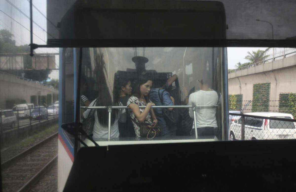 In this Tuesday, Aug. 11, 2015 photo, a passenger leans on the railing in a crowded train of the Manila Metro Rail Transit System that runs in between Epifanio de los Santos Avenue (EDSA) during rush hour traffic in the financial district of Makati, south of Manila, Philippines. Manila and other cities are choked with construction sites for office and apartment towers. But spending on roads, railways and other unglamorous but essential infrastructure collapsed after the 1997 financial crisis and has yet to recover. (AP Photo/Aaron Favila)