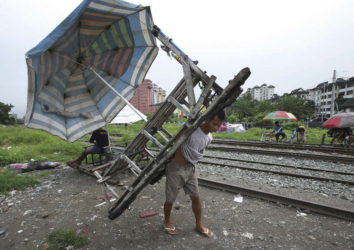 In this Wednesday, Aug. 12, 2015 photo, Filipino Ramil Santos parks his metal-wheeled cart with benches fashioned from scrap wood as he waits for passengers along the railway in Manila, Philippines. Manila and other cities are choked with construction sites for office and apartment towers. But spending on roads, railways and other unglamorous but essential infrastructure collapsed after the 1997 financial crisis and has yet to recover. (AP Photo/Aaron Favila)