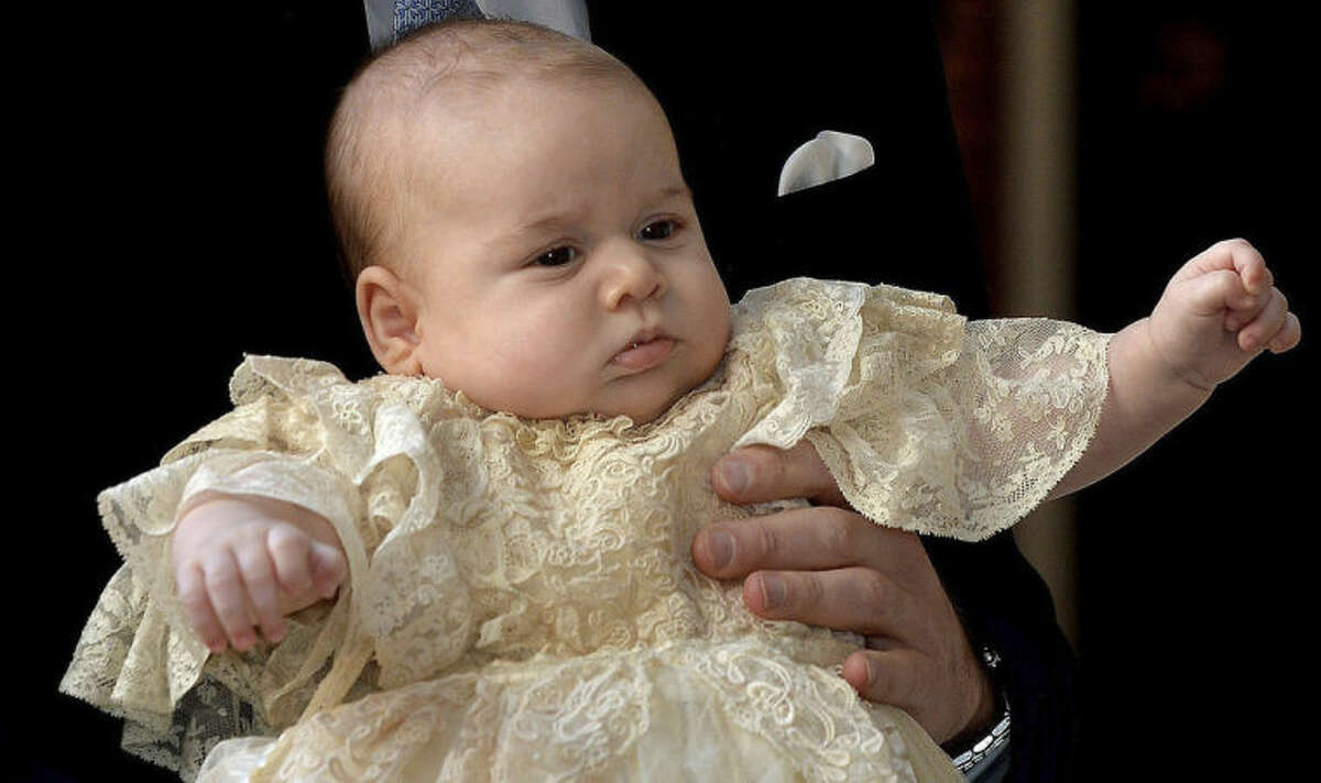 FILE - This is a Wednesday Oct. 23, 2013 file photo of Britain's Prince George as he is held by his father Prince William as they arrive at Chapel Royal in St James's Palace in London, for the christening of the three month-old Prince. Prince George turns 1 on Tuesday. While he may be too young to appreciate it, the milestone is causing a nationwide frenzy. Editorial writers call him a symbol of hope, newspaper headlines hail him as "Gorgeous George" and one published a 24-page glossy magazine chronicling his first 12 months. (AP Photo/John Stillwell/Pool, File)