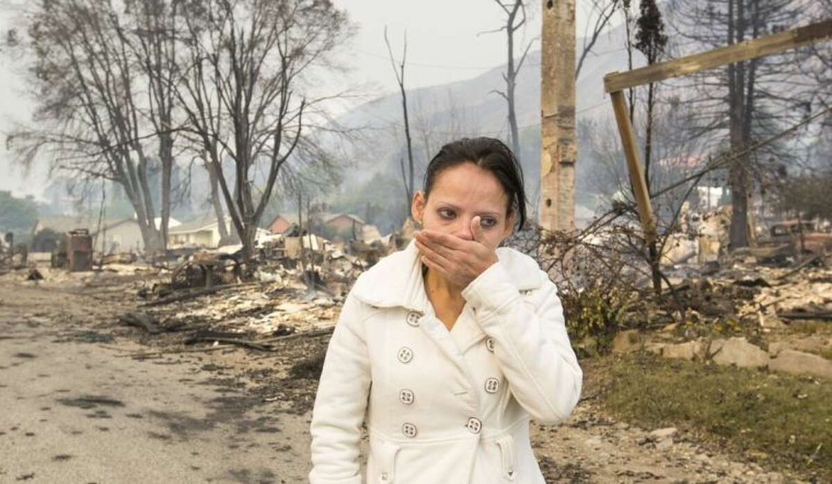 Emma Franco, views her destroyed mobile home on Friday, July 18, 2014, after several homes were destroyed in Pateros, Wash., along South Dawson Street near Warren Street on Thursday evening. Tens of thousands of acres are burning in four major fires around the state, destroying homes and forcing residents to pack up and run. (AP Photo/The Seattle Times, Mike Siegel)
