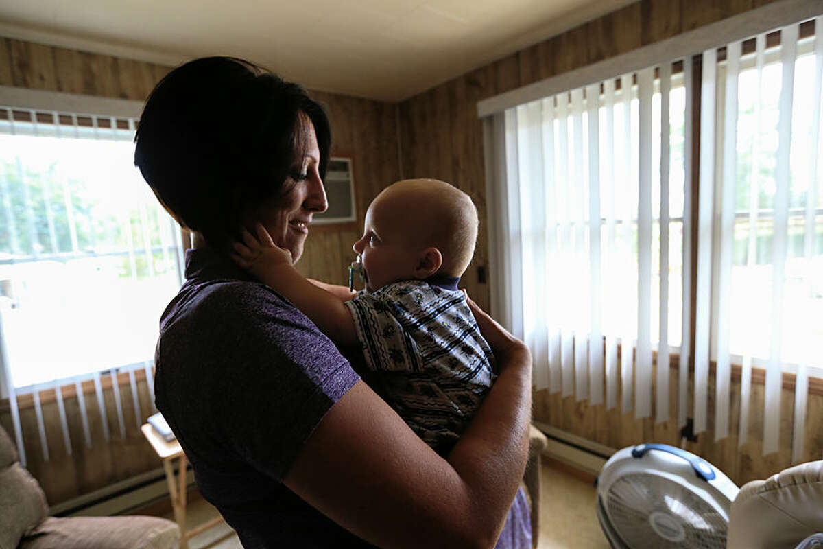 In this Thursday, Aug. 13, 2015, photo, nurse Kerri Lutjens looks over Rylan Hofer, an 8-month-old Hutterite, during a home visit at the Tschetter Colony near Olivet, S.D. Lutjens has spent the past few years gaining the trust of several communities of Hutterites, a deeply religious people, who live in insular farming communities in the Plains, Upper Midwest and Canada. (AP Photo/Nati Harnik)