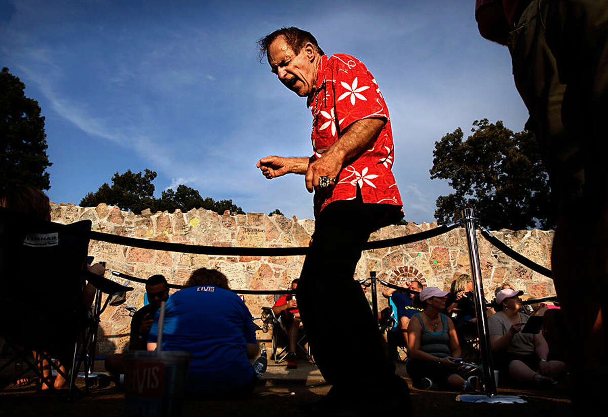 John Plant, 70, from Schenectady, NY serenades Elvis fans waiting in line in front of Graceland Saturday, Aug. 15, 2015, before a vigil to mark the 38th anniversary of the death of Elvis Presley. Thousands of Elvis fans gathered at the gates of Graceland for the annual event. (Jim Weber/The Commercial Appeal via AP)