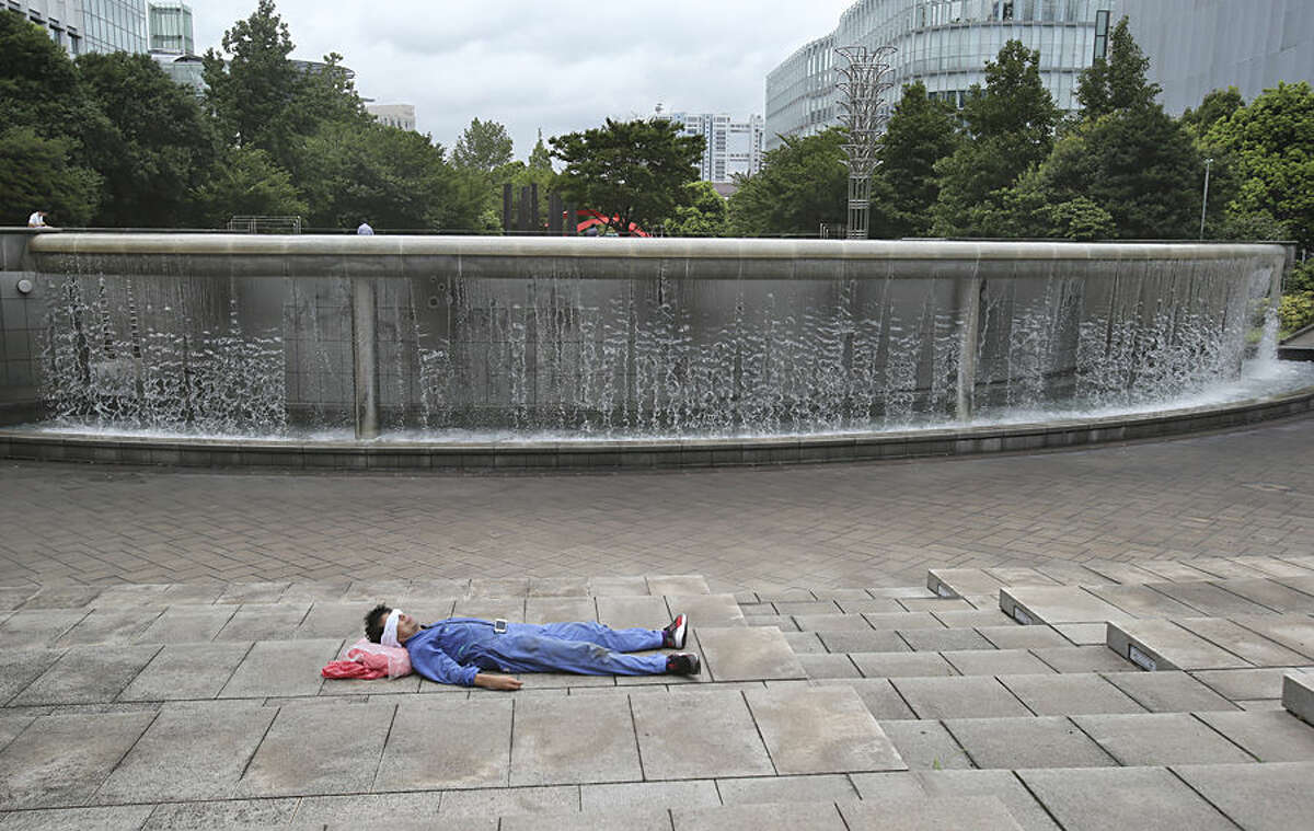 A man rests near a fountain during a lunch time in Tokyo, Monday, Aug. 17, 2015. (AP Photo/Koji Sasahara)