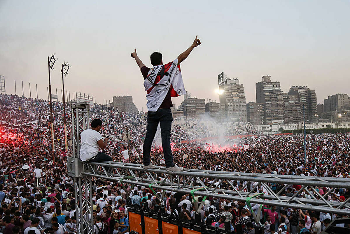 In this July 31, 2015 photo, Zamalek soccer fans celebrate after winning the Egyptian League at Zamalek Club in Cairo, Egypt. The hardcore fan base Ultras White Knights did not celebrate the winning of the team out of respect for more than 20 soccer fans who were crushed to death outside an air defense stadium in Cairo after police fired tear gas to break up the crowd waiting in a fenced, narrow corridor to watch. Police accused the fans of attacking the force, and rioting to enter the stadium on Feb. 8, 2015. (AP Photo/Mohammed El Raai)