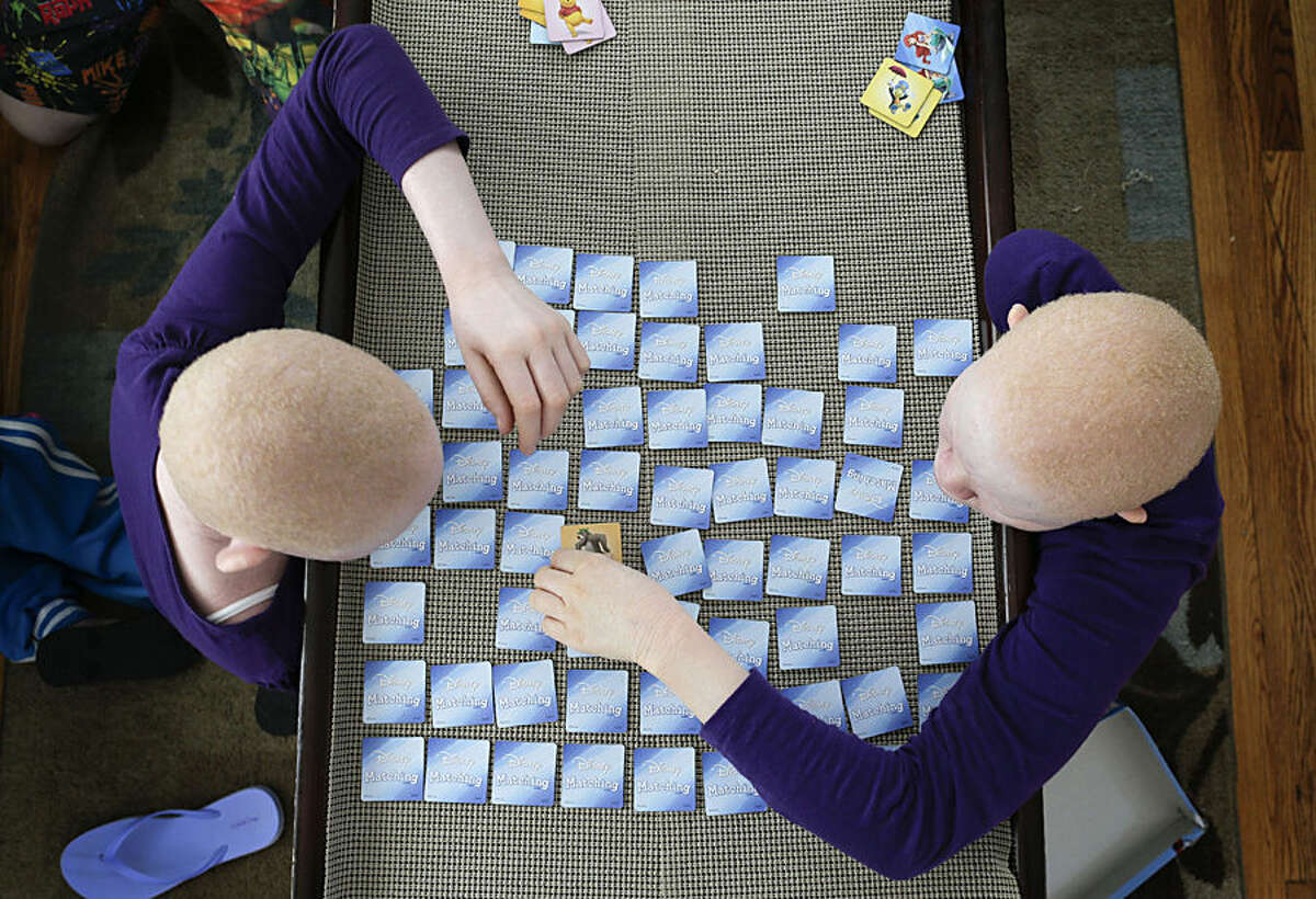 Pendo Noni, left, and Kabula Masanja play a memory card game in New York on Tuesday, July 28, 2015. One out of every 1,400 citizens in Tanzania has albinism. Pendo and Kabula were attacked and dismembered in the belief that their body parts will bring wealth. (AP Photo/Julie Jacobson)