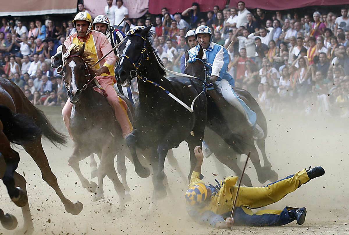 A rider falls during the ancient Palio of Siena, the famous break-neck bareback horse race run, in Siena, Italy, Monday, Aug. 17, 2015. (AP Photo/Paolo Lazzeroni)