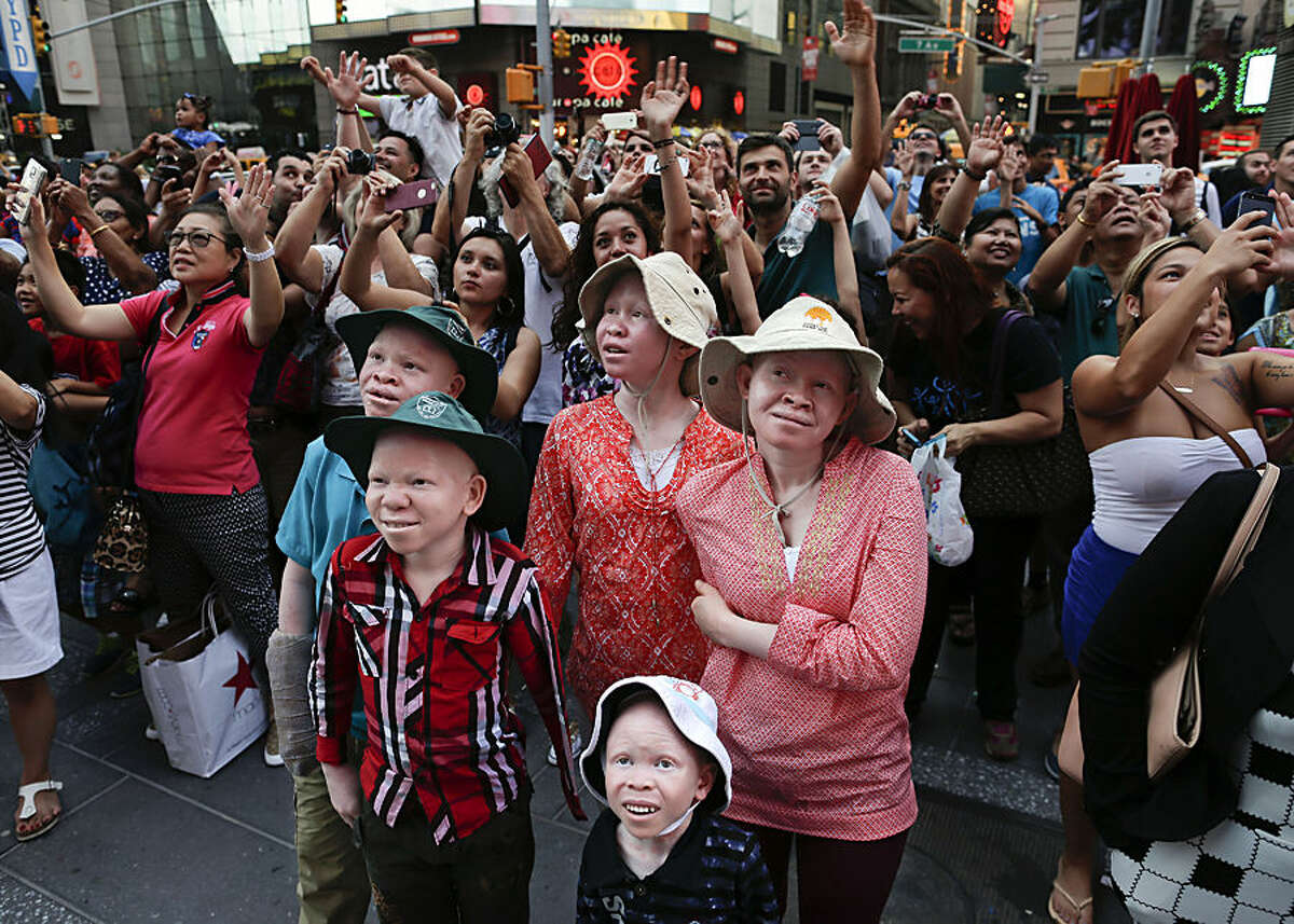 Emmanuel Rutema, Kabula Masanja, Pendo Noni, Mwigulu Magesa and Baraka Lusambo watch the Revlon live camera with a crowd of other tourists during a visit to Times Square in New York on Tuesday, July 28, 2015. People with the genetic condition of albinism, characterized by a lack of pigment, are often referred to in Tanzania as ghosts, or zero zero, which in Swahili signifies someone who is less than human. (AP Photo/Julie Jacobson)