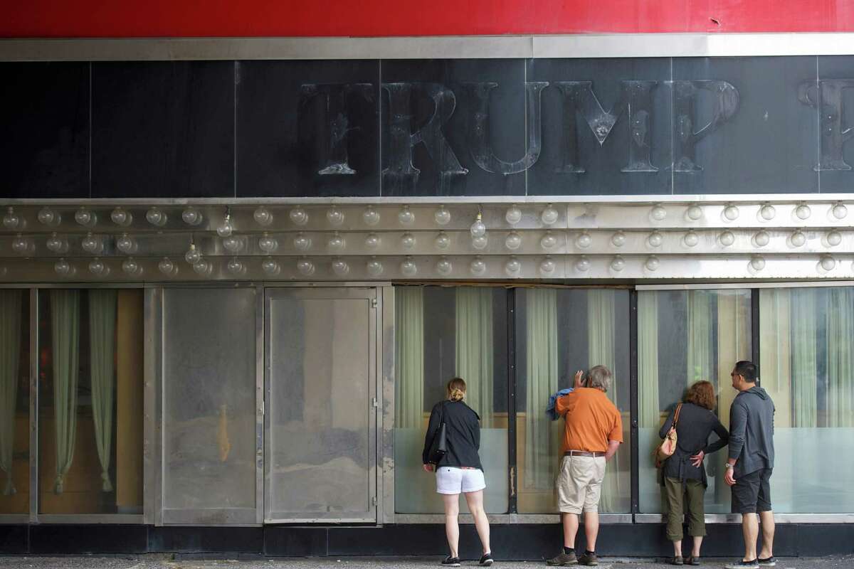Canadian tourists peer into the windows of the now closed Trump Plaza Casino in Atlantic City, N.J. His other casinos in the struggling seaside resort town - Trump Marina and Trump Taj Mahal - have been sold.