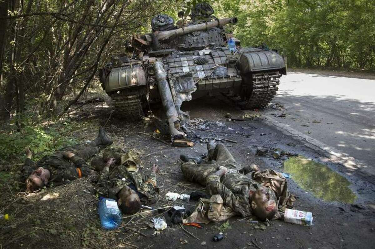 EDITORS NOTE GRAPHIC CONTENT - Bodies of crew members lie next to a destroyed Ukrainian tank in the northern outskirts of city of Donetsk, eastern Ukraine Tuesday, July 22, 2014. The soldiers were reportedly killed in fighting between rebels and government forces Monday. (AP Photo/Dmitry Lovetsky)
