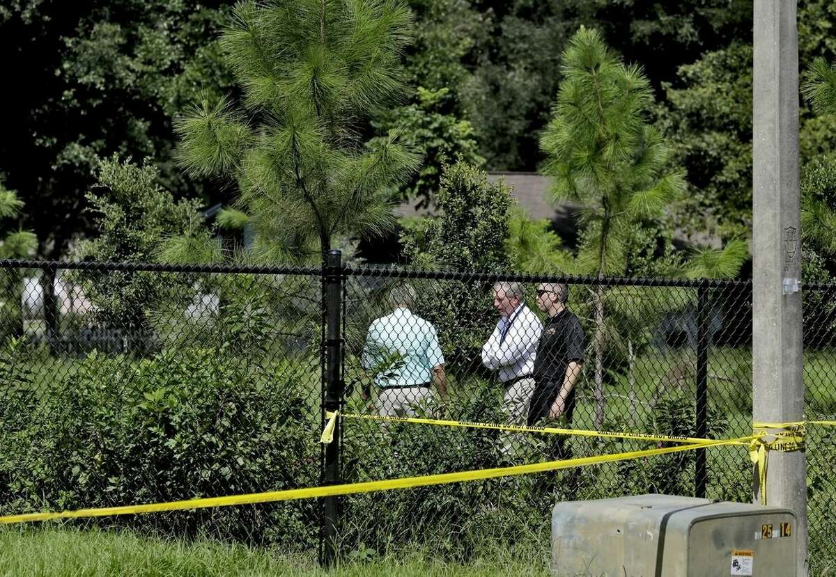 Ron Spiller, director of code enforcement for Hillsborough County, center, surveys the property where a sinkhole reopened, Wednesday, Aug. 19, 2015, in Seffner, Fla. The sinkhole reopened in the exact same location where one swallowed a man as he slept in his bed more than two years ago. The new hole is 17 feet wide by 20 feet deep, according to Spiller. In March 2013, Jeffrey Bush was asleep in his bedroom on the property when the floor collapsed and he fell in. His body was never recovered. His brother, Jeremy Bush, was in the house and tried to rescue him, even jumping into the hole. (AP Photo/Chris O'Meara)