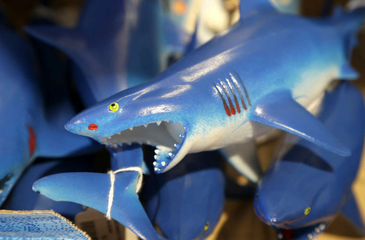 In this July 2, 2014 photo, a bin is filled with plastic toy sharks in a souvenir shop in Chatham, Mass. With growing sightings of great white sharks off Cape Cod, local entrepreneurs are feeding the frenzy with their shark-themed memorabilia and apparel. (AP Photo/Steven Senne)