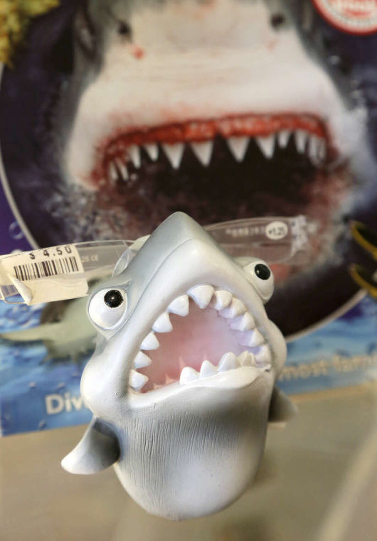 In this July 2, 2014 photo, an eye glass holder in the shape of a shark rests on a shelf in a souvenir shop in Chatham, Mass. With growing sightings of great white sharks off Cape Cod, local entrepreneurs are feeding the frenzy with their shark-themed memorabilia and apparel. (AP Photo/Steven Senne)