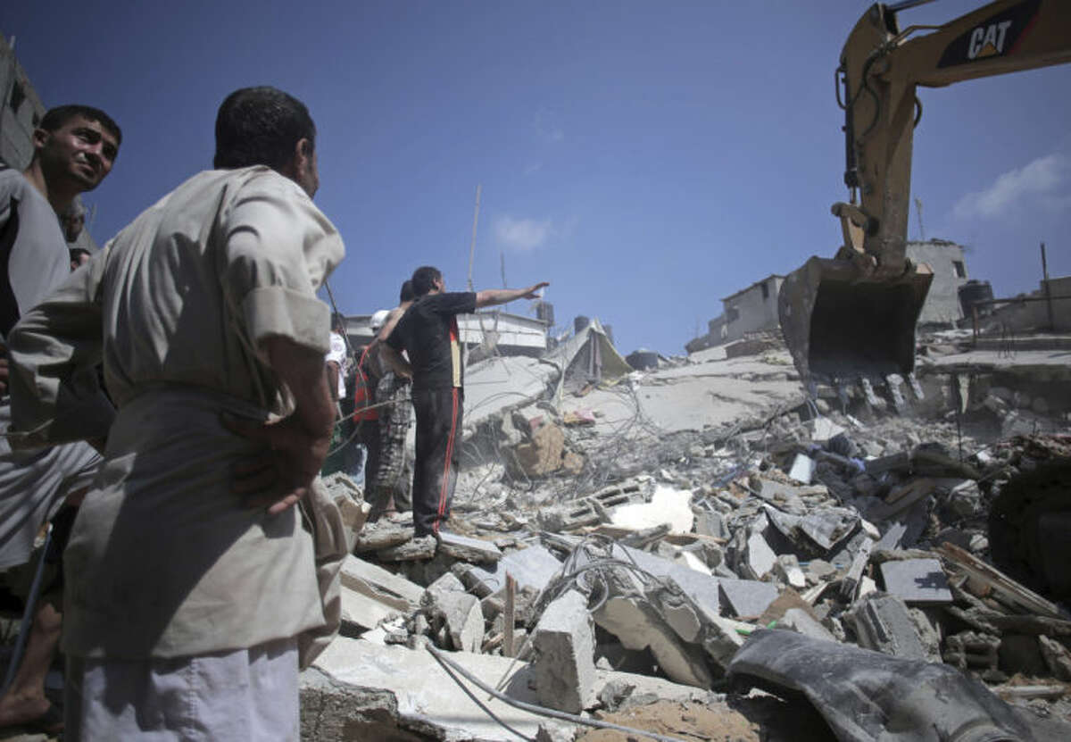 Palestinian rescuers search for bodies and survivors in the rubble of homes which were destroyed by an Israeli missile strike, in Gaza City, Monday, July 21, 2014. On Sunday, the first major ground battle in two weeks of Israel-Hamas fighting exacted a steep price, killing scores Palestinians and over a dozen Israeli soldiers and forcing thousands of terrified Palestinian civilians to flee their devastated Shijaiyah neighborhood, which Israel says is a major source for rocket fire against its civilians. (AP Photo/Khalil Hamra)