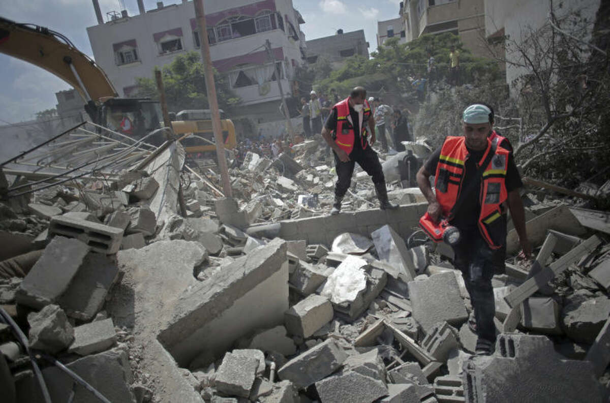 Palestinian rescue workers search for survivors under the rubble of a house was destroyed by an Israeli missile strike, in Gaza City, Monday, July 21, 2014. On Sunday, the first major ground battle in two weeks of Israel-Hamas fighting exacted a steep price, killing scores of Palestinians and over a dozen Israeli soldiers and forcing thousands of terrified Palestinian civilians to flee their devastated Shijaiyah neighborhood, which Israel says is a major source for rocket fire against its civilians. (AP Photo/Khalil Hamra)