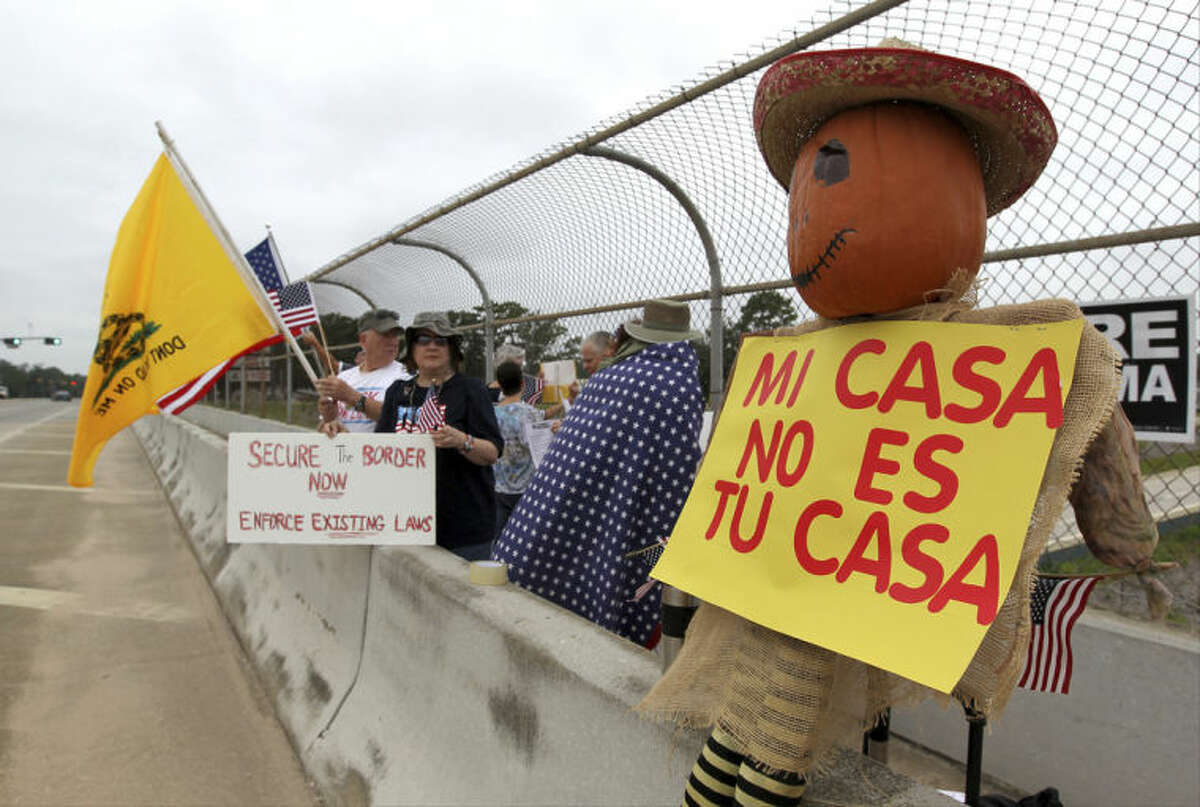 Protesters line the overpass during a protest against people who immigrate illegally, Saturday, July 19, 2014, in Conroe, Texas. Texas Gov. Rick Perry took his border security criticisms to an audience of Hispanic ministers in San Antonio, telling them the federal government should put more Border Patrol troops on the ground and drones in the air to secure the Texas-Mexico border. (AP Photo/Conroe Courier, Jason Fochtman)