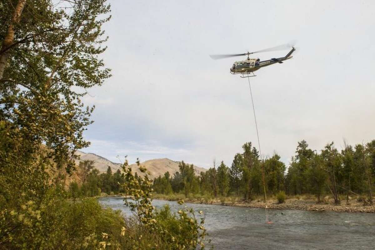 A helicopter refills with water in the Methow River onSunday, July 20, 2014, in Carlton, Washington. The Carlton Complex fires have swept the region covering over 215,000 acres of land and destroying over 100 structures. Fire crews have been called in from all over the country in order to help contain the fire. (AP Photo/The Seattle Times, Maddie Meyer) SEATTLE OUT; USA TODAY OUT; MAGS OUT; TELEVISION OUT; NO SALES; MANDATORY CREDIT TO BOTH THE SEATTLE TIMES AND THE PHOTOGRAPHER