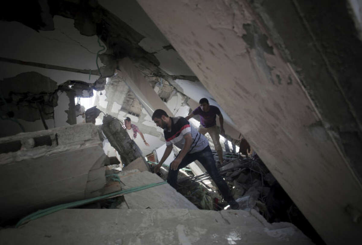 Palestinians search for survivors under the rubble of a house was destroyed by an Israeli missile strike, in Gaza City, Monday, July 21, 2014. On Sunday, the first major ground battle in two weeks of Israel-Hamas fighting exacted a steep price, killing scores of Palestinians and over a dozen Israeli soldiers and forcing thousands of terrified Palestinian civilians to flee their devastated Shijaiyah neighborhood, which Israel says is a major source for rocket fire against its civilians. (AP Photo/Khalil Hamra)