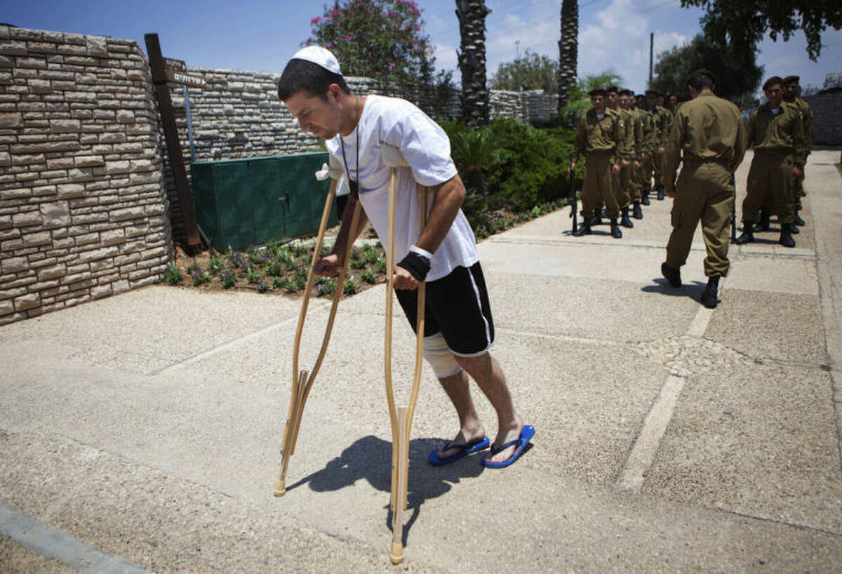 An Israeli wounded soldier arrives for the funeral of Maj. Tzafrir Bar-Or, 32, one of 13 solider's who were killed in several separate incidents in Shijaiya on Sunday, at the military cemetery in Holon, Monday, July 21, 2014. On Sunday, the first major ground battle in two weeks of Israel-Hamas fighting exacted a steep price, killing scores of Palestinians and more than a dozen Israeli soldiers and forcing thousands of terrified Palestinian civilians to flee their devastated Shijaiyah neighborhood, which Israel says is a major source for rocket fire against its civilians. The 13 Israeli soldiers were killed in Shijaiya, in gun battles and rocket attacks. In the deadliest, Gaza fighters detonated a bomb near an armored personnel carrier, killing seven soldiers inside, the army said. In another incident, three soldiers were killed when they became trapped in a burning building, it said. (AP Photo/Dan Balilty)