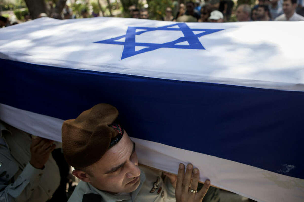 Israeli soldiers carry the coffin of Maj. Tzafrir Bar-Or, 32, one of 13 solider's who were killed in several separate incidents in Shijaiya on Sunday, at the military cemetery in Holon, Monday, July 21, 2014. On Sunday, the first major ground battle in two weeks of Israel-Hamas fighting exacted a steep price, killing scores of Palestinians and more than a dozen Israeli soldiers and forcing thousands of terrified Palestinian civilians to flee their devastated Shijaiyah neighborhood, which Israel says is a major source for rocket fire against its civilians. The 13 Israeli soldiers were killed in Shijaiya, in gun battles and rocket attacks. In the deadliest, Gaza fighters detonated a bomb near an armored personnel carrier, killing seven soldiers inside, the army said. In another incident, three soldiers were killed when they became trapped in a burning building, it said. (AP Photo/Dan Balilty)
