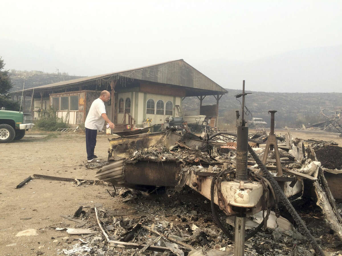Steve Surgeon surveys the ruins after he lost everything he owned except his home in a wildfire on the outskirts of Okanogan, Wash., Sunday, Aug. 23, 2015. He said he stayed as the fire raced over a ridge and barreled down toward his home, flames lapping just feet from his back porch. Surgeon estimates he lost more than $100,000 worth of property, including his shop, his motorcycle, several cars, a travel trailer, and all of his tools.(AP Photo/Brian Skoloff)