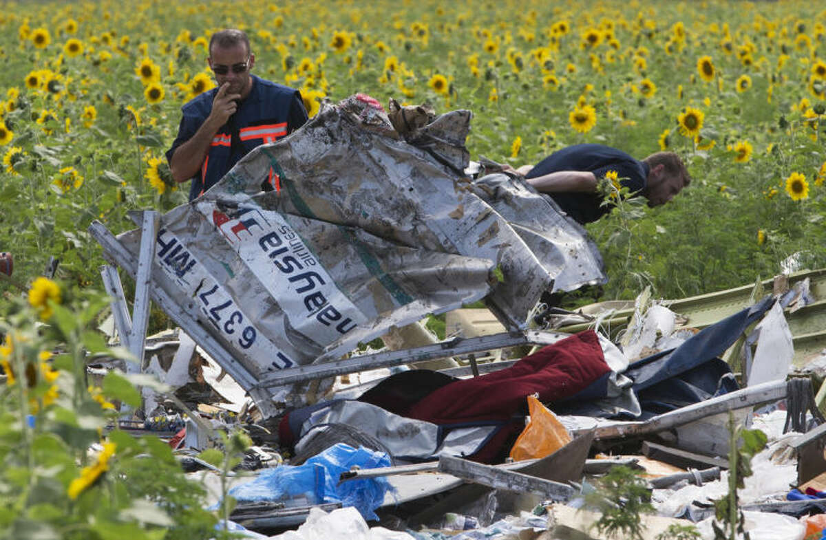 Dutch investigators examine pieces of the crashed Malaysia Airlines Flight 17 in the village of Rassipne, Donetsk region, eastern Ukraine, Friday, July 25, 2014. (AP Photo/Dmitry Lovetsky)