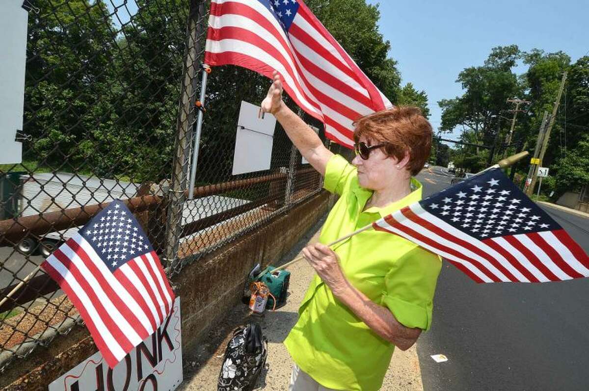 Hour Photo/Alex von Kleydorff On Strawberry Hill ave Friday, Nancy Krysiak waves a flag as motorists on I95 Northbound honk their horns in support. The New England Overpasses for America group were protesting immigration amnesty for the recent wave of children crossing the border into the US