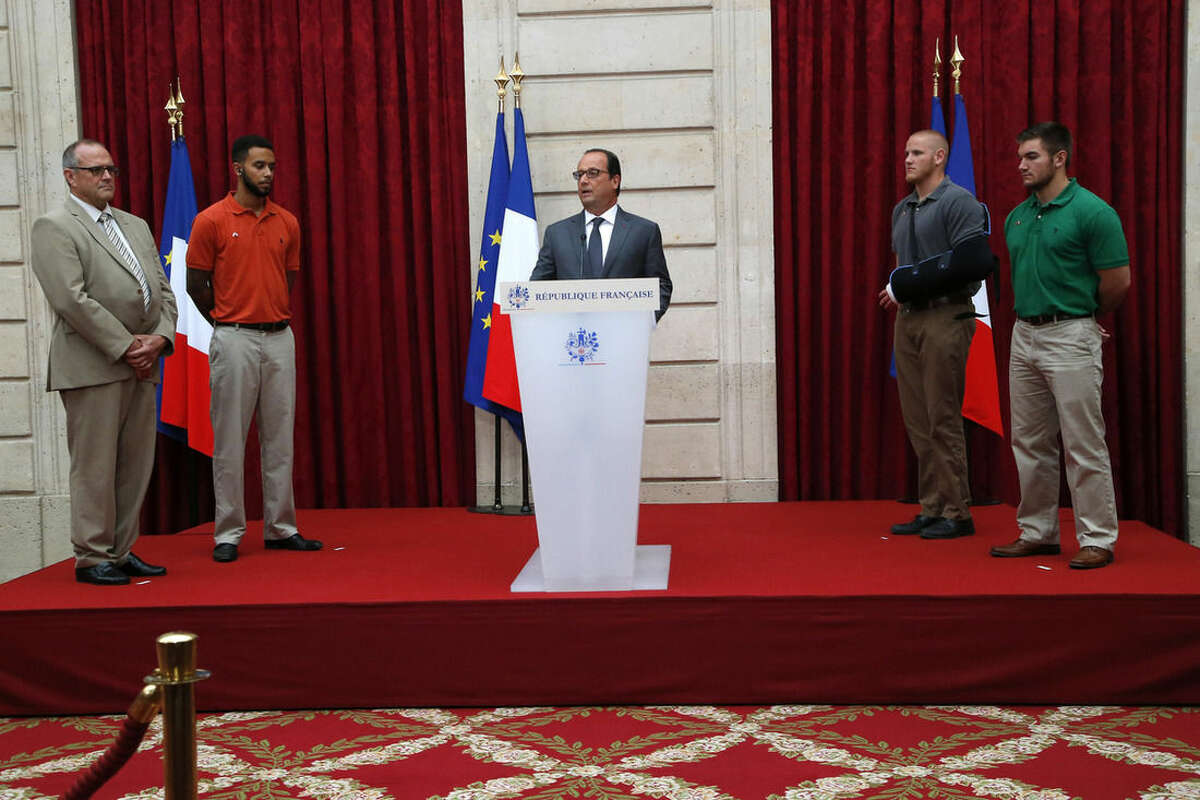 From the left, British businessman Chris Norman, Anthony Sadler, a senior at Sacramento University in California , U.S. Airman Spencer Stone, second right, and U.S. National Guardsman from Roseburg, Oregon, Alek Skarlatos, right, listen to French President Francois Hollande, center, at the Elysee Palace, Monday Aug.24, 2015 in Paris, France. Three Americans and a British man who took down a heavily armed man on a passenger train speeding through Belgium have received France's top honor.(AP Photo/Michel Euler, Pool)