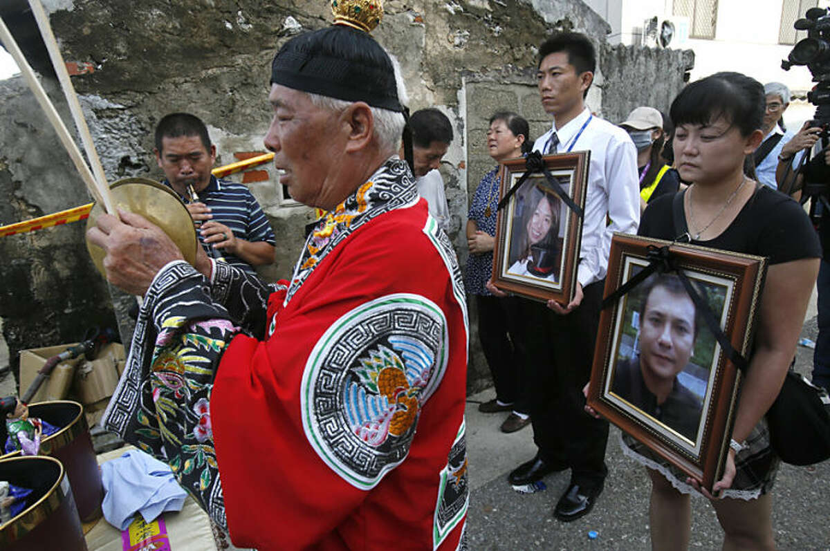 Relatives of victims killed in the TransAsia Airways Flight GE222 crash pray with the victims' portraits during a makeshift ceremony at the crash site on the outlying island of Penghu, Taiwan, Thursday, July 24, 2014. Stormy weather on the trailing edge of Typhoon Matmo was the likely cause of the plane crash that killed more than 40 people, the airline said Thursday. (AP Photo/Wally Santana)