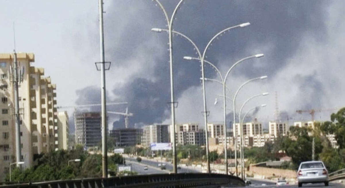 FILE - In this Sunday, July 13, 2014 file image made from video by The Associated Press, smoke rises from the direction of Tripoli airport in Tripoli, Libya. The United States shut down its embassy in Libya on Saturday, July 26, 2014, and evacuated its diplomats to neighboring Tunisia under U.S. military escort amid a significant deterioration in security in Tripoli as fighting intensified between rival militias, the State Department said. (AP Photo/File)