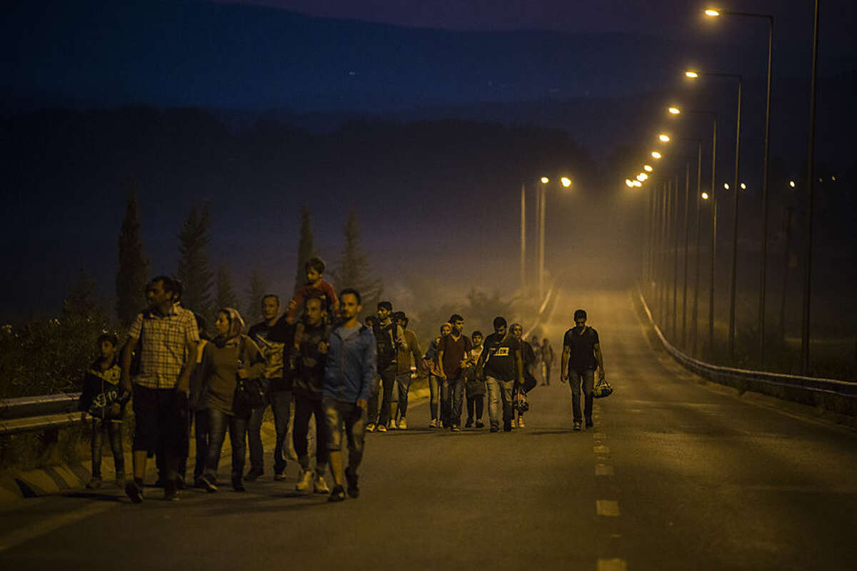 Syrian refugees walk along the roads of the border town of Idomeni , northern Greece to cross the border and enter Macedonia, on Tuesday Aug. 25, 2015. The U.N.’s refugee agency said it expects 3,000 people to cross Macedonia daily in the coming days. Greece has been overwhelmed this year by record numbers of migrants who have been arriving on a number of Greek islands.(AP Photo/Santi Palacios)