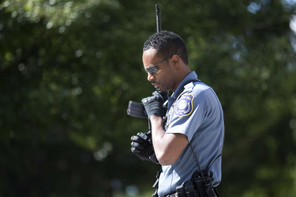 A police officer carries his weapon near the scene of a shooting at the Mercy Fitzgerald Hospital in Darby, Pa. on Thursday, July 24, 2014. A prosecutor said a gunman opened fire inside the psychiatric unit leaving one hospital employee dead and a second injured before being critically wounded himself. (AP Photo)