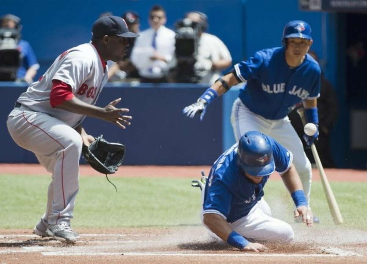 Toronto Blue Jays' Melky Cabrera, right, slides safely home past Boston Red Sox starting pitcher Rubby De La Rosa, left, after a passed ball during first inning baseball action in Toronto on Thursday, July 24, 2014. Blue Jays' Munenori Kawasaki, rear, watches the play. (AP Photo/The Canadian Press, Nathan Denette)