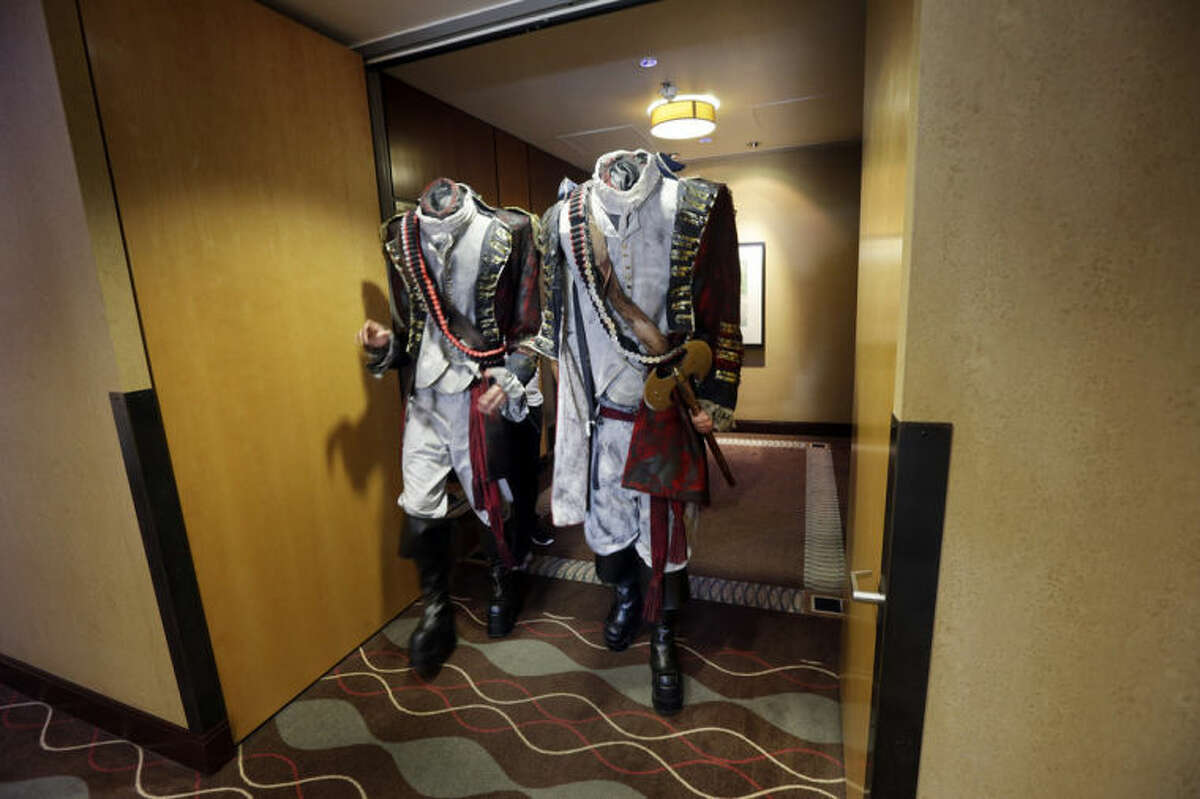 FILE - In this July 19, 2013 file photo, two men dressed as headless characters get off a hotel elevator in San Digeo. Like Batman responding to a beaming Bat signal in the sky, pop-culture fans are flocking to San Diego for the 45th annual Comic-Con. The four-day festival celebrating comic books, costumes and other popular arts kicks off with a preview Wednesday night, July 23, 2014, and goes full force Thursday at the San Diego Convention Center. (AP Photo/Gregory Bull, file)