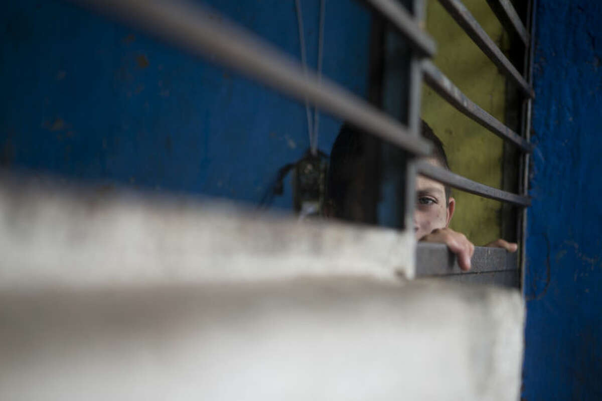 In thus Thursday, July 17, 2014 photo, a boy peers out through the door of a cell-like room inside The Great Family group home in Zamora, Mexico. After a police raid on the refuse-strewn group home, residents of the shelter told authorities that some employees beat residents, fed them rotting food or locked them in a tiny "punishment" room. Shelter residents were still being kept at the home while officials look for places to transfer them. (AP Photo/Rebecca Blackwell)