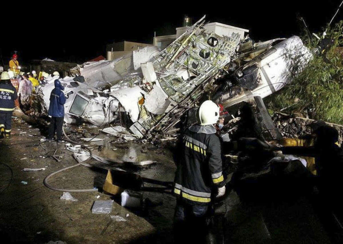 Rescue workers survey the wreckage of TransAsia Airways flight GE222 which crashed while attempting to land in stormy weather on the Taiwanese island of Penghu, late Wednesday, July 23, 2014. A plane landing in stormy weather crashed outside an airport on a small Taiwanese island late Wednesday, and a transport minister said dozens of people were trapped and feared dead. (AP Photo/Wong Yao-wen)