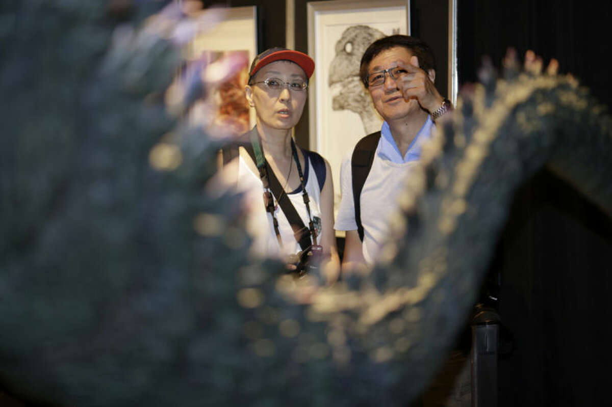Japanese Godzilla devotees Yoshihiko Horie, right, and his wife Shizue look at a scale model of Godzilla at Godzilla Expo in Tokyo, Friday, July 25, 2014. She feels her life has been defined by Godzilla. She met her husband after a painful divorce through their mutual interest in Godzilla. And she has taken her children and their friends to Godzilla movies. She gets teary-eyed, remembering when the Japanese Godzilla series ended a decade ago. (AP Photo/Eugene Hoshiko)