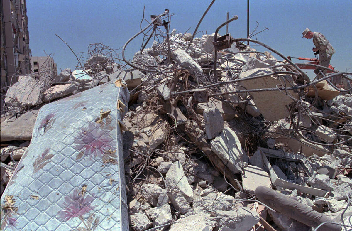 FILE - In this June 27, 1996 file photo, a U.S. Air Force officer climbs a pile of rubble to photograph the devastated building in Dhahran, Saudi Arabi where a truck bomb destroyed the eight story building behind Tuesday and killed 19 U.S. servicemen, injuring hundreds. A man suspected in the 1996 bombing of the Khobar Towers residence at a U.S. military base in Saudi Arabia has been captured, a U.S. official tells The Associated Press. Ahmed al-Mughassil , described by the FBI in 2001 as the head of the military wing of Saudi Hezbollah, is suspected of leading the attack that killed 19 U.S. service personnel and wounded almost 500 people.(AP Photo/Greg Marinovich, File)