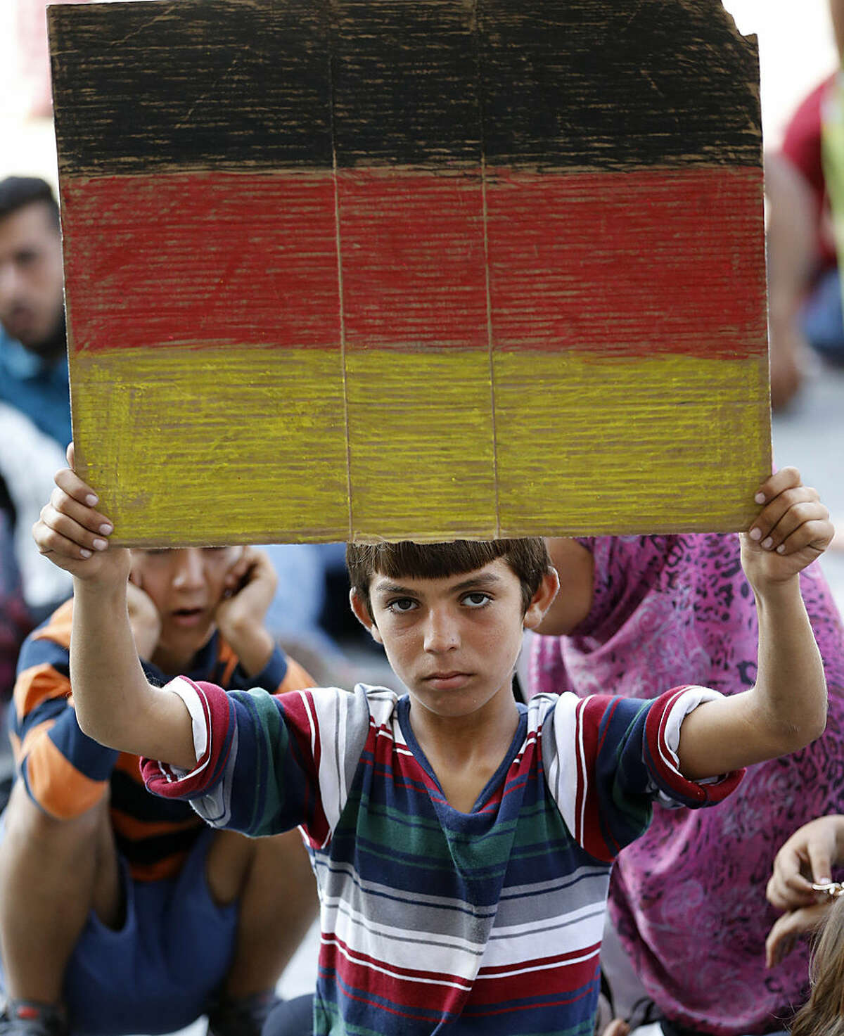 A young boy holds a German flag in front of the railway station in Budapest, Hungary, Thursday, Sept. 3, 2015. Over 150,000 migrants have reached Hungary this year, most coming through the southern border with Serbia, and many apply for asylum but quickly try to leave for richer EU countries.(AP Photo/Frank Augstein)