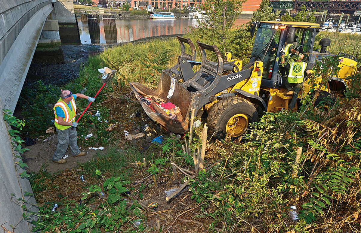 Hour photo / Erik Trautmann Norwalk Department of Public Works employees and Norwalk police remove a homeless encampment from underneath the Stafolino Bridge Wednesday.