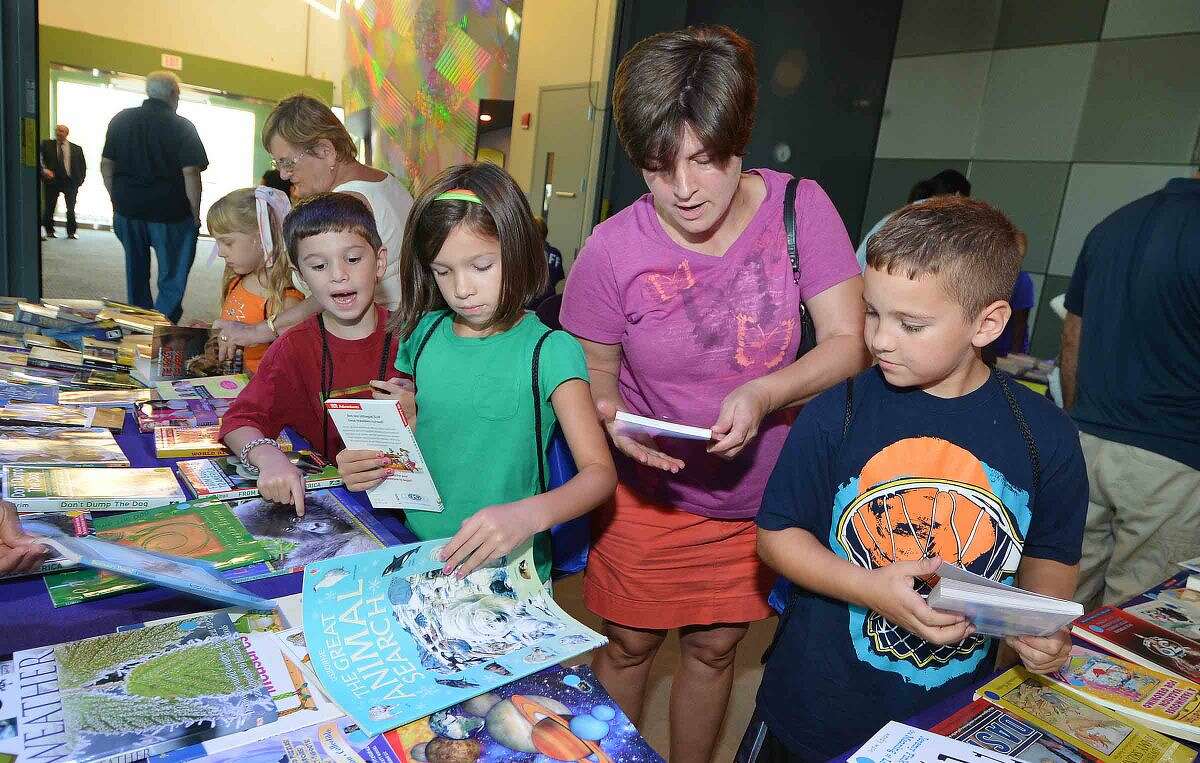 Hour Photo/Alex von Kleydorff Kelly Batzios helps family and friends Nicholas Ari Stizabal, Sofia Ari Stizabal and Jaden Tamburro pick out some books at their reading level at the Norwalk Reads book table during Back to School night at Stepping Stones Museum for Children