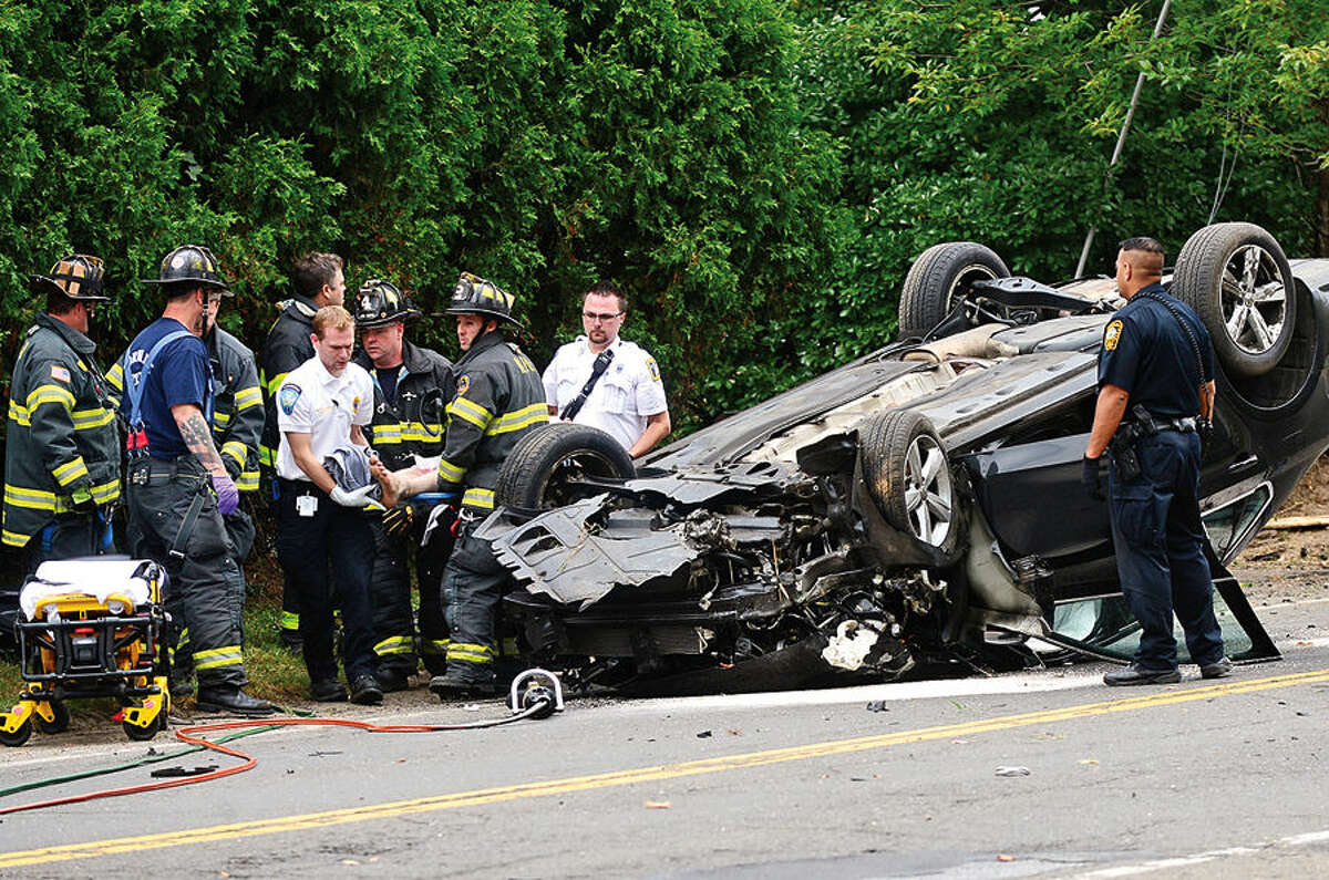 Hour photo / Erik Trautmann Norwalk emergency personnel work to free the driver of a volkswagon sedan that rolled over on Newtown Ave in a single-car accident Friday morning. The driver was conscious and transported to Norwalk Hospital.