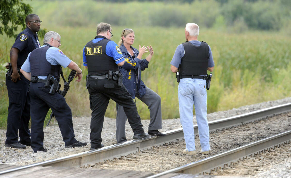 Police officers confer while searching for suspects in the shooting of a police officer Tuesday, Sept. 1, 2015 outside Fox Lake, Ill. Fox Lake Police Lt. Charles Joseph Gliniewitz was shot and killed while pursuing a group of suspicious men. Police with helicopters, dogs and armed with rifles are conducting a massive manhunt in northern Illinois for the individuals believed to be involved in the death of the three-decade member of the department and a father of four sons. (AP Photo/Michael Schmidt)