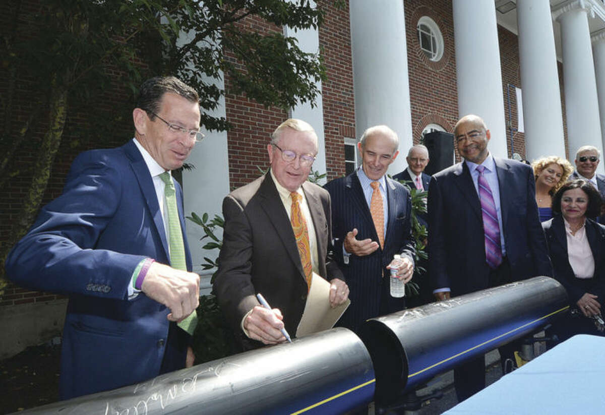 Hour photo/Alex von Kleydorff Gov. Dan Malloy, left, watches Wilton First Selectman Bill Brennan sign a section of natural gas pipe with help from Northeast Utilities CEO Tom May and Yankee Gas President Rodney Powell. Brennan signed, then drew a dollar sign to show how much residents, businesses and the town might save with the new Natural gas line in Wilton.