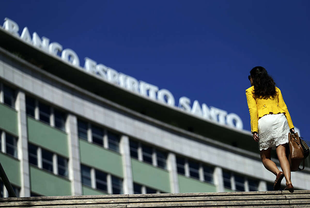 A woman exits a subway station next to a Portuguese bank Banco Espirito Santo's offices building, in Lisbon, Monday, Aug. 4, 2014. Portugal's biggest banking scandal, which compelled authorities Sunday to put up euro 4.9 billion ($6.6 billion) to prevent the collapse of ailing Banco Espirito Santo, raised key questions about how regulators were apparently hoodwinked and focused minds on the European banking system stress tests, whose results are due in October. (AP Photo/Francisco Seco)