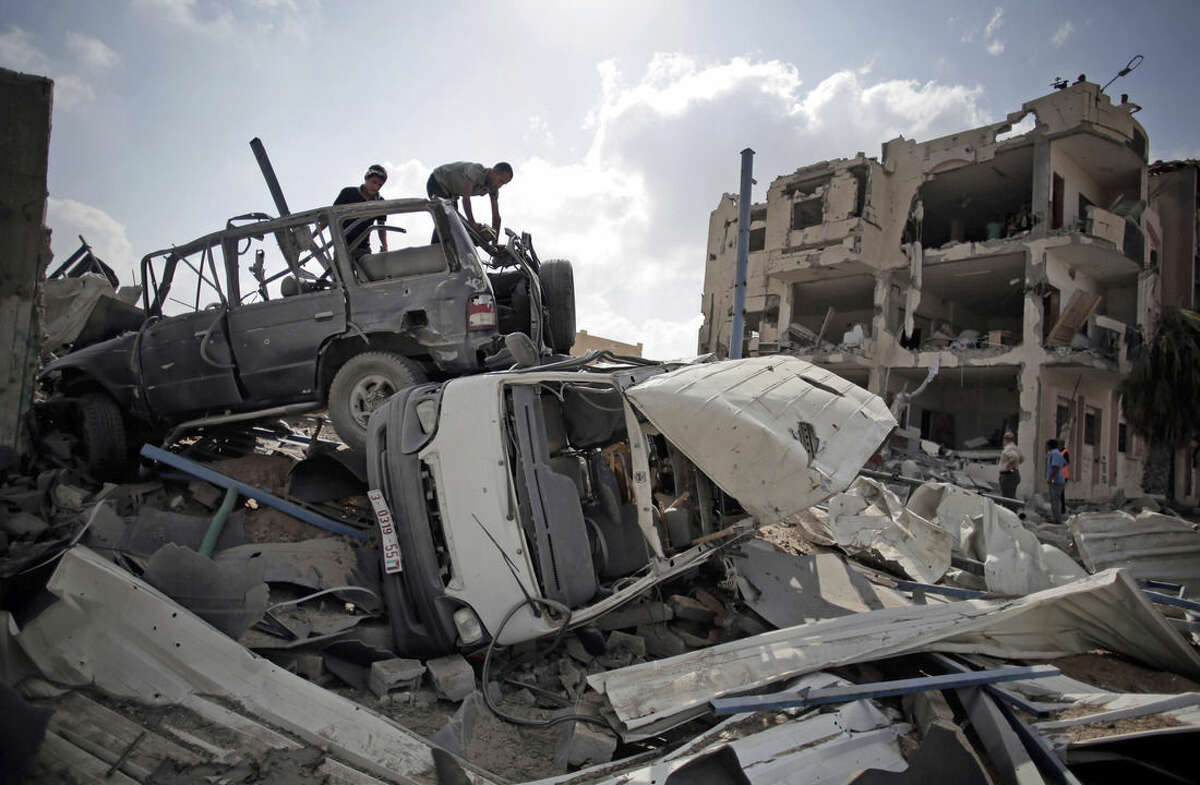 Palestinians search destroyed cars in Rafah's district of Shawkah in the southern Gaza Strip, Tuesday, Aug. 5, 2014. The attack at the Shawkah district east of the Gaza town of Rafah drew what was by far the heaviest shelling by the Israeli military in the Gaza war, killing nearly 100 people that day alone and instantly unraveling a three-day ceasefire shortly after it came into force. (AP Photo/Khalil Hamra)